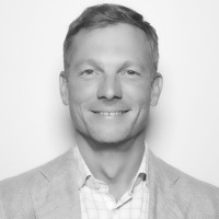Black-and-white headshot of smiling man in blazer