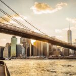 Brooklyn Bridge spanning New York City skyline at sunset.