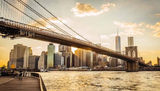 Brooklyn Bridge spanning New York City skyline at sunset.