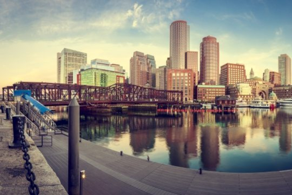 Boston skyline reflected in harbor beside a steel bridge