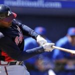 Baseball player swinging bat during game.