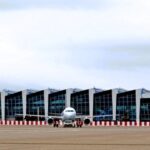 Airplane at airport terminal with modern architecture.