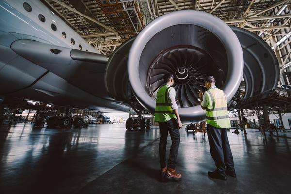 Technicians inspecting large jet engine in hangar
