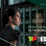 Businesswoman looking out window, text: From Business to World.