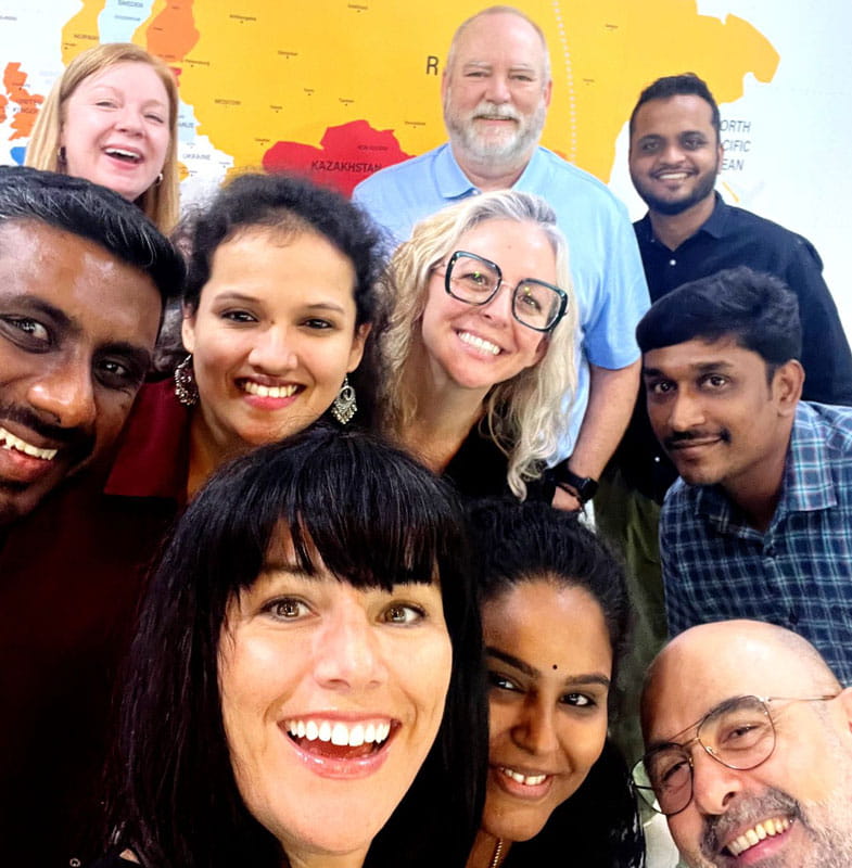 Diverse group smiling in selfie before world map