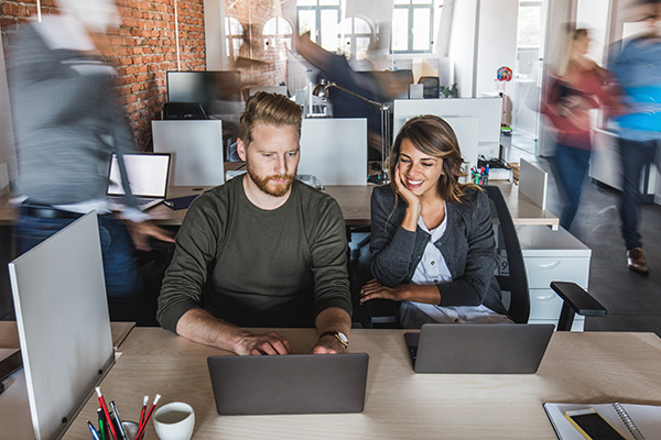 Two colleagues working in a busy office