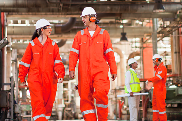 Industrial workers in orange coveralls walking in factory