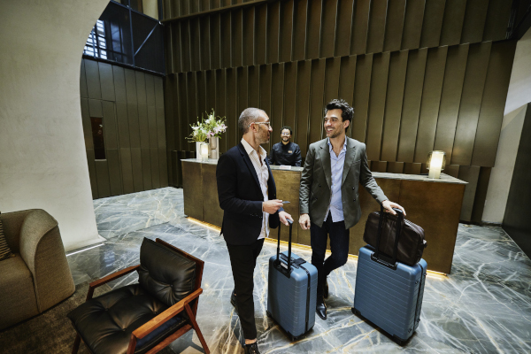 Two men with suitcases in hotel lobby.