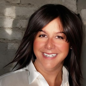 Smiling woman with dark hair and white shirt.