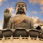 Giant Buddha statue under a vibrant sky.
