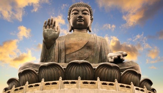 Giant Buddha statue under a vibrant sky.