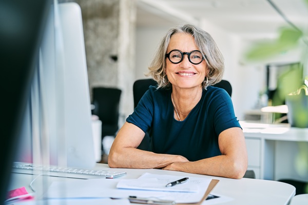 Smiling woman with glasses seated at office desk