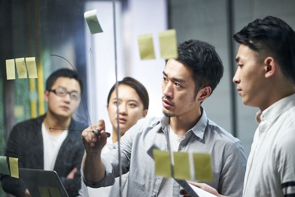 Team brainstorming with sticky notes on glass wall