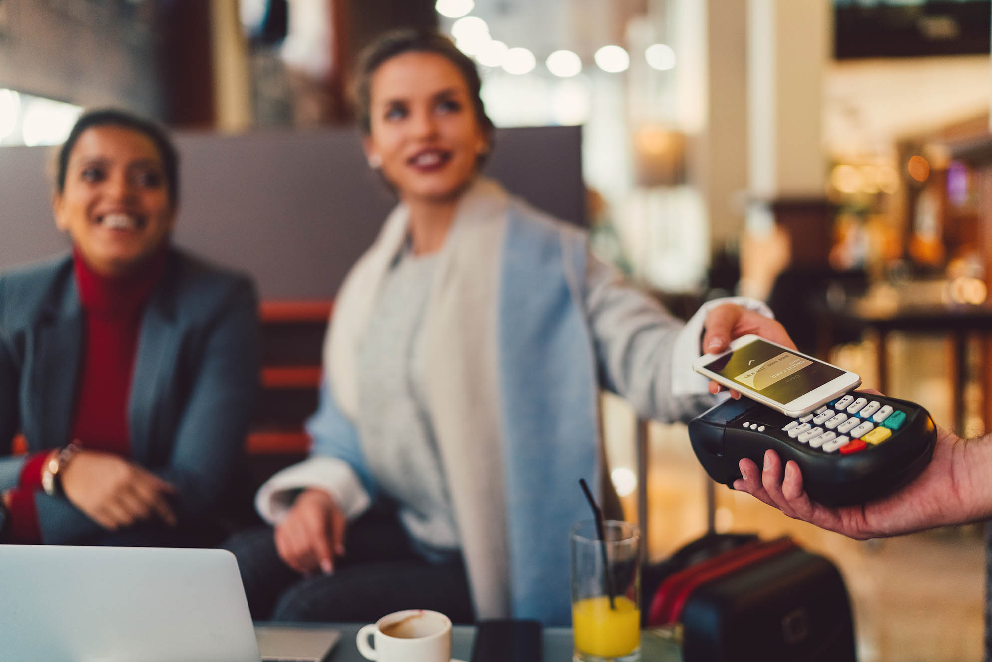 corporate travel payment by a women making contactless payment in the restaurant