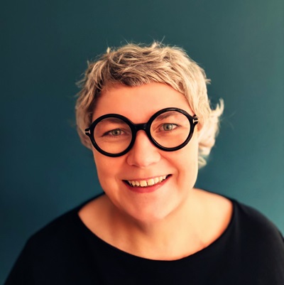 Smiling person with glasses against blue background.