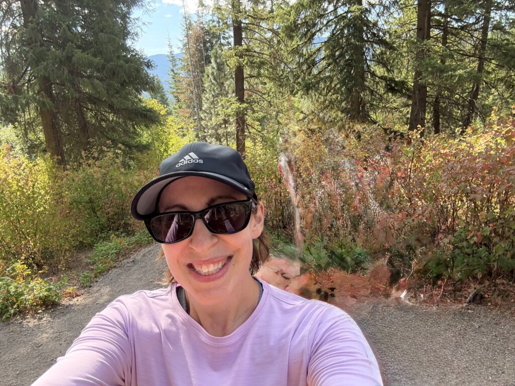 Smiling person hiking in forested mountain area.