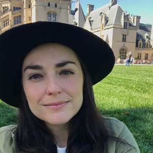 Person wearing hat in front of historic building.