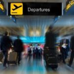 Airport departures area with travelers and luggage.