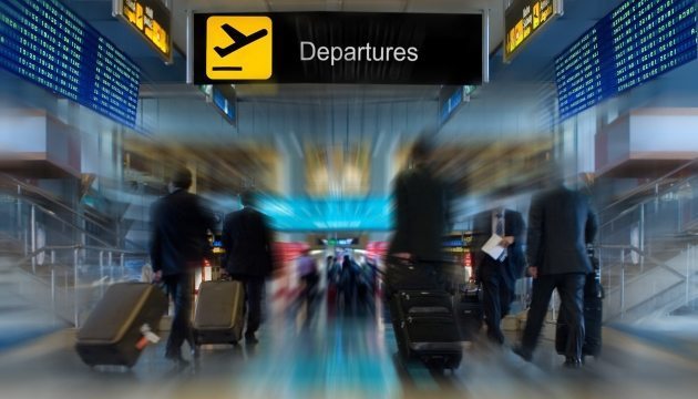Airport departures area with travelers and luggage.