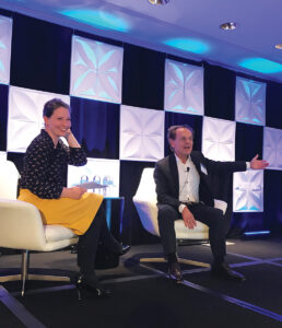 Two people speaking at a conference panel discussion.