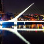 Illuminated modern bridge over river at night