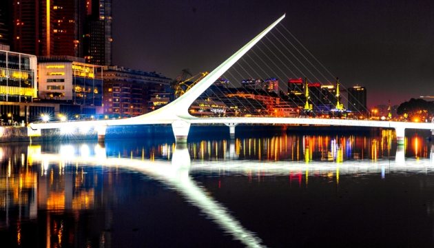 Illuminated modern bridge over river at night