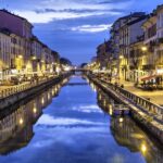 Milan canal at sunset with illuminated buildings.
