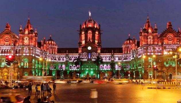 Mumbai's CST illuminated at night with colorful lights.