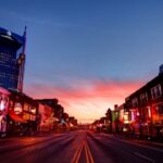 Neon-lit street with sunset in background