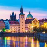 Colorful Prague cityscape at sunset with river view.