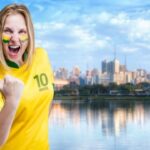 Cheering fan wearing Brazil jersey by city skyline.