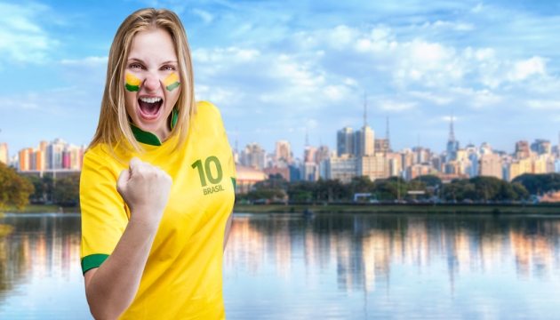 Cheering fan wearing Brazil jersey by city skyline.