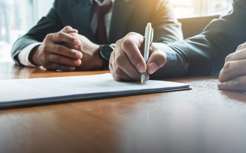 Businessperson signing a legal document at a desk.
