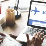 Person booking flight tickets online on laptop.