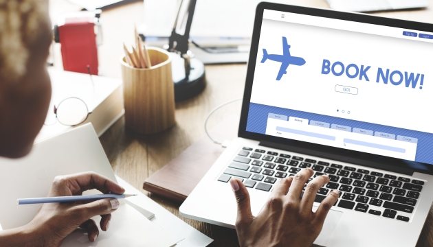 Person booking flight tickets online on laptop.