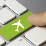 Finger pressing green airplane key on keyboard.