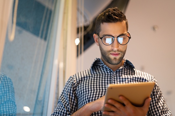 Man wearing glasses uses tablet indoors