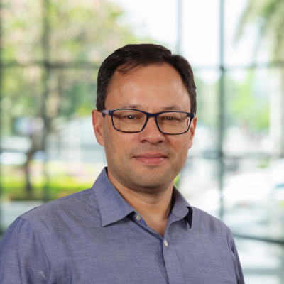 Person in office setting, wearing glasses and a shirt.