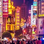 Busy Asian city street with bright neon signs.