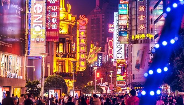 Busy Asian city street with bright neon signs.