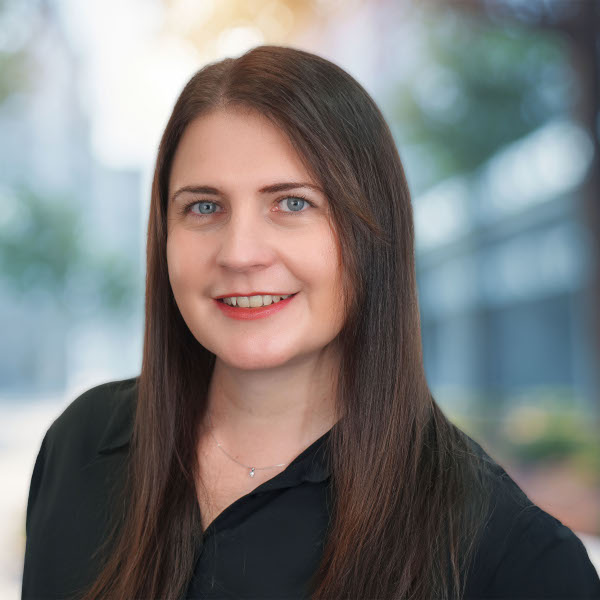 Smiling person with long hair and outdoor background.
