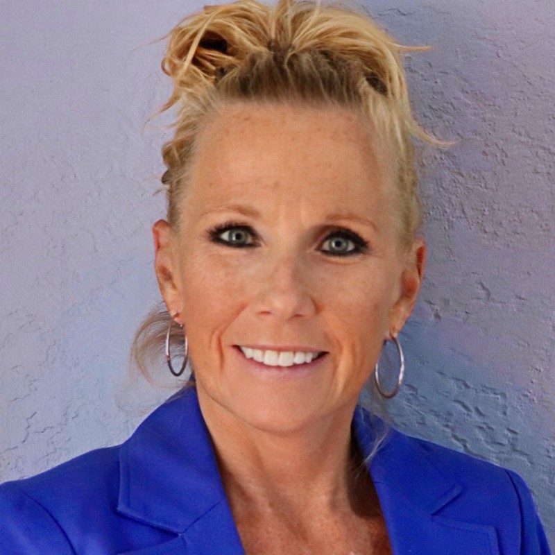 Smiling woman in blue blazer against purple wall