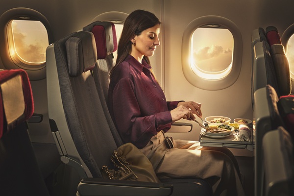 Woman enjoying meal on airplane during sunset flight