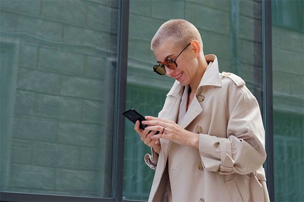 Person smiling at phone in beige coat