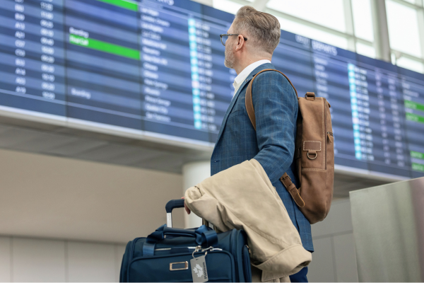 Business traveler checks airport departure board with luggage