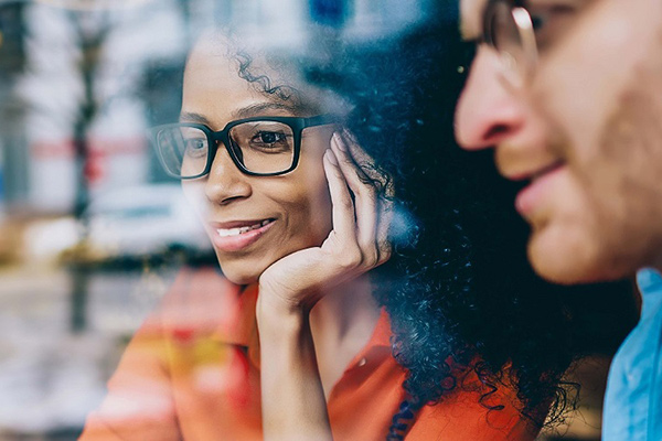 Smiling woman with glasses beside blurred companion
