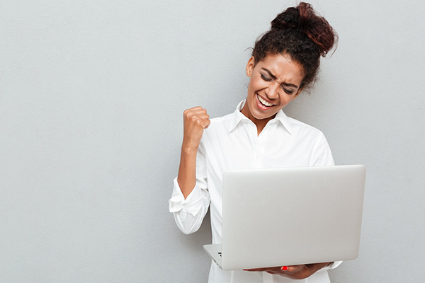 Woman celebrates success while using a laptop