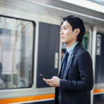 Businessman using smartphone near train.