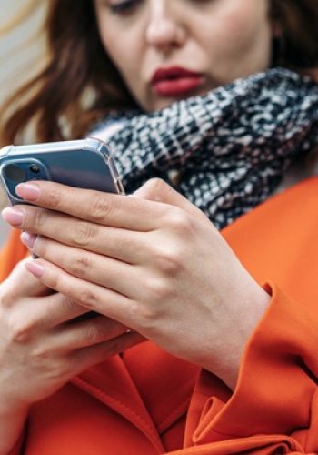 Woman in orange coat texting on smartphone