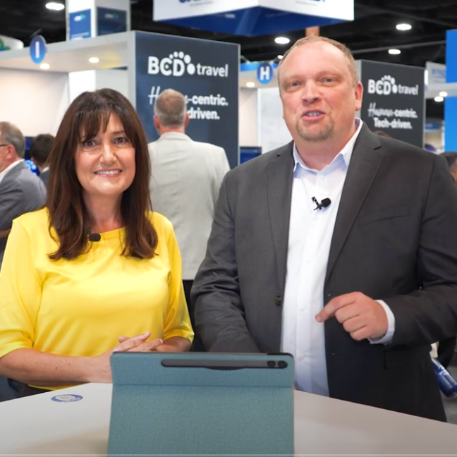 Two professionals discussing at a business conference booth.